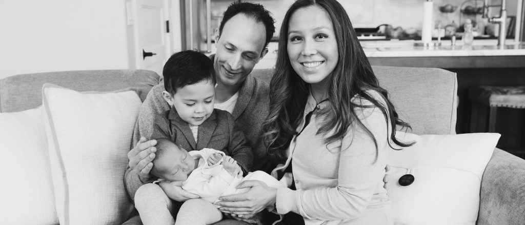 Family sitting on couch with newborn and toddler