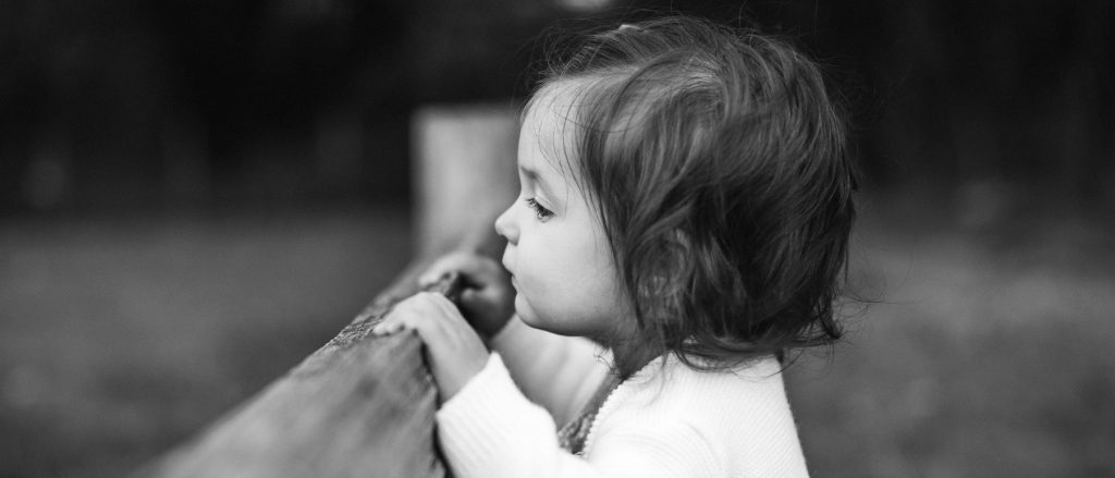 Black and white profile of a toddler outdoors.