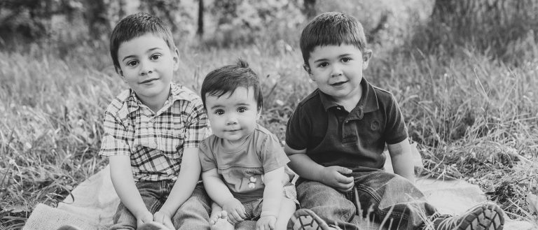 Three children sitting on grass in black and white