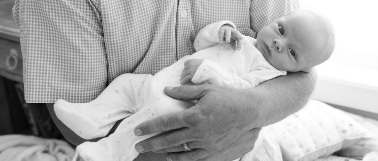 Man holding baby in arms, black and white photo.