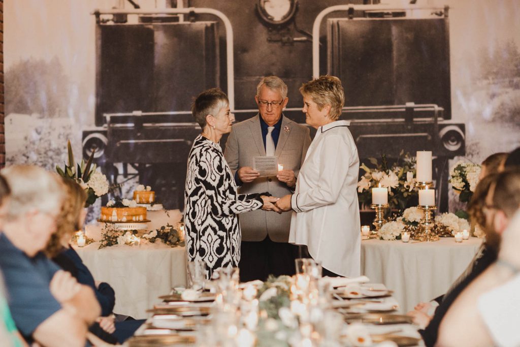 Two women exchanging vows at wedding ceremony.