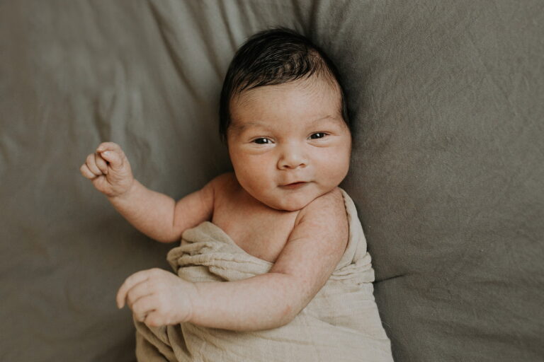 Smiling baby wrapped in beige blanket