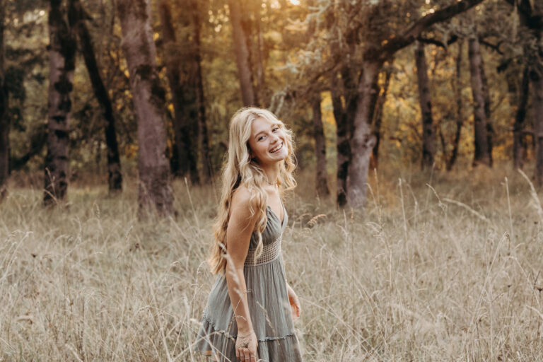 Smiling woman in forest clearing at sunset