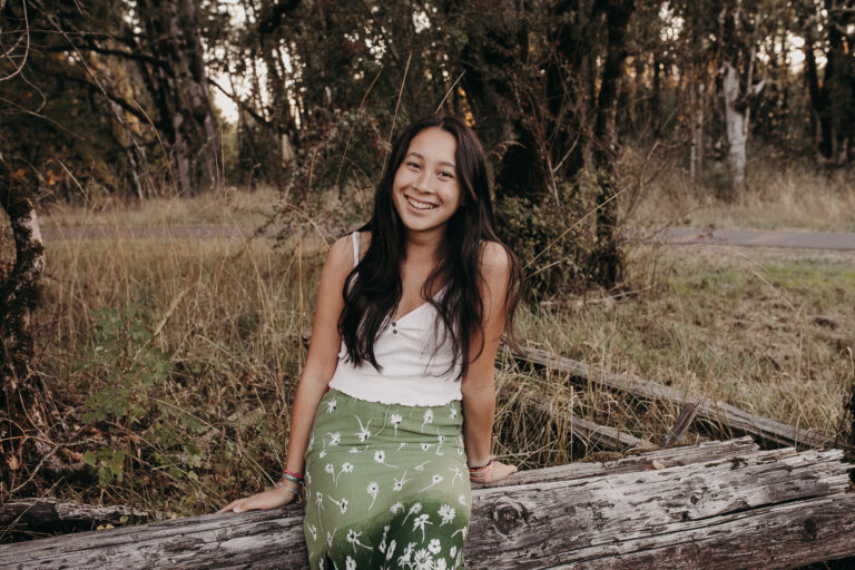 Smiling woman sitting on log in forest