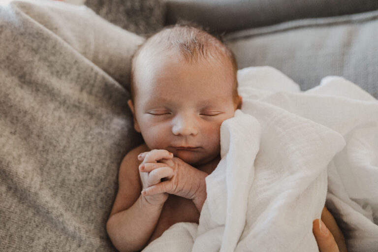 Newborn baby sleeping wrapped in white blanket