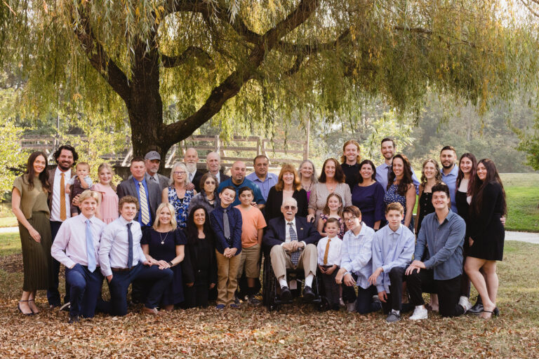 Over 30 members of a family gather under the wide branches of a weeping willow.