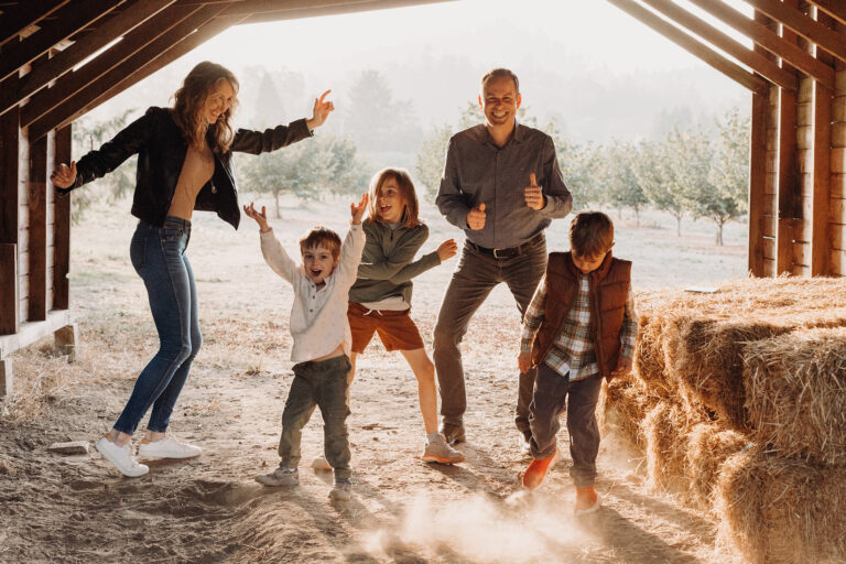 A family of three young boys and their parents form an impromptu dance party in their barn.