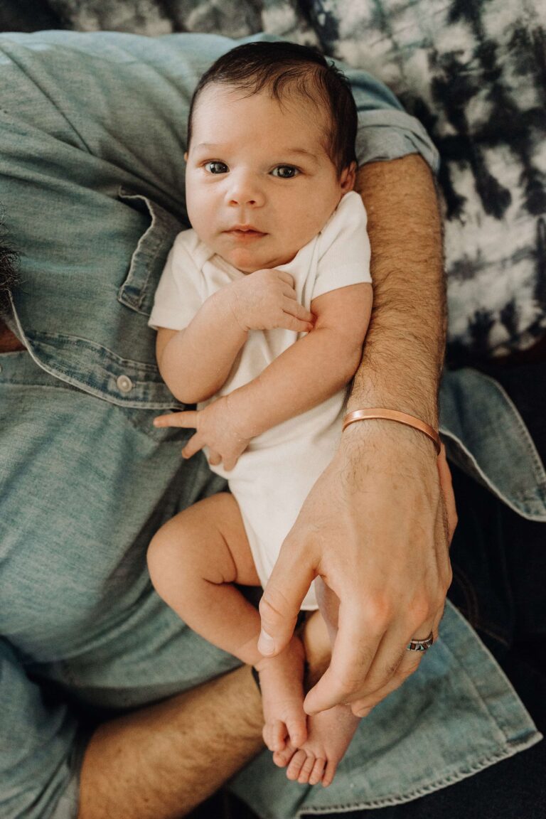 Close-up of a baby staring up into the camera as she's cradled in her fathers arms.