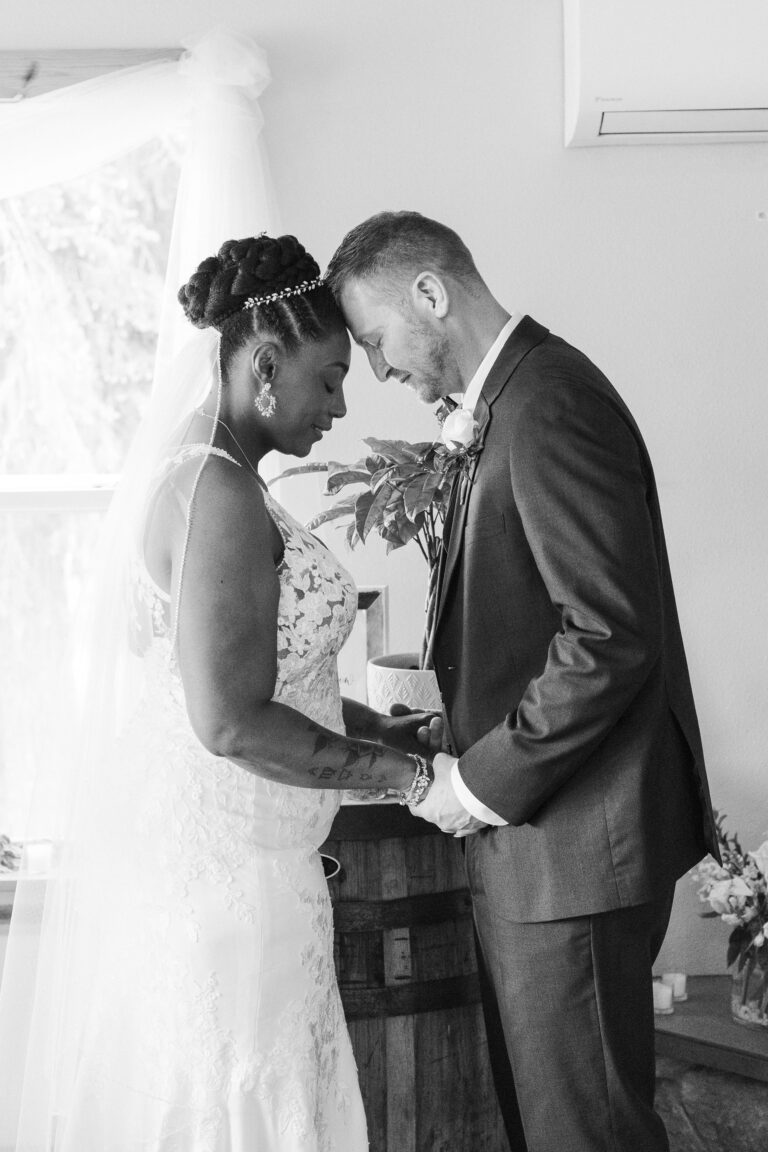 A bride and groom share an intimate moment alone with heads bowed together and eyes closed.