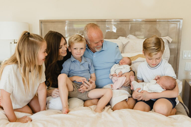 Family sitting together on a bed with babies.