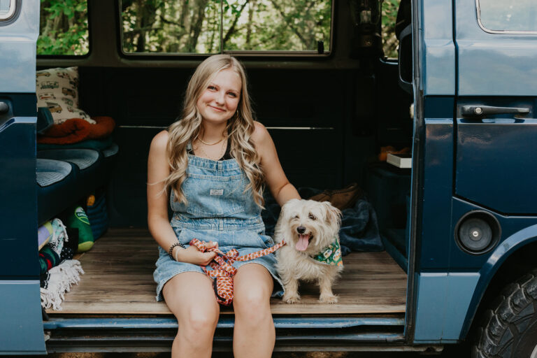Woman and dog sitting in blue van