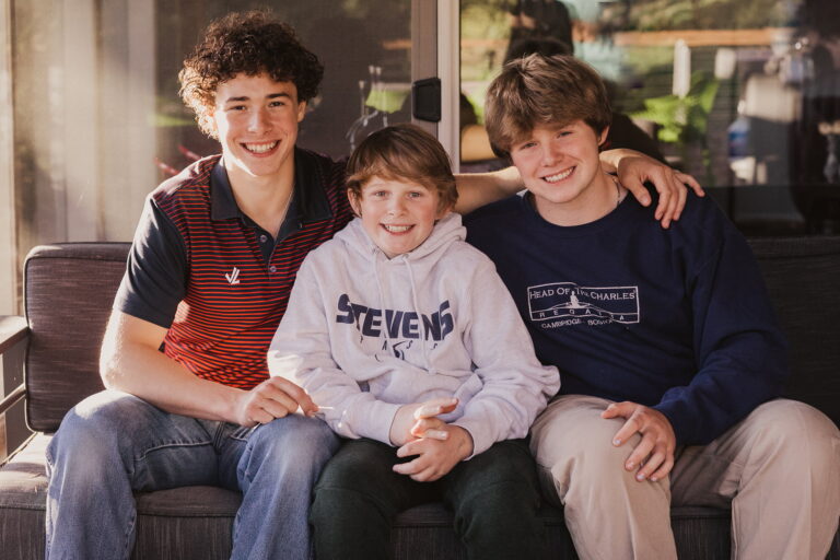 Three smiling brothers sitting together outside.