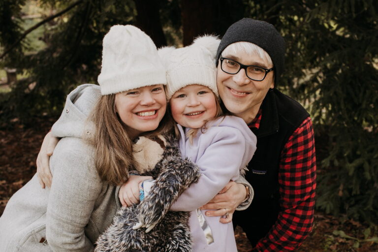 Family smiling in winter clothing outdoors.