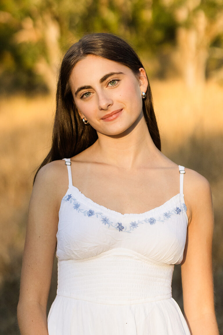 A lovely young woman in a white dress, exuding grace and beauty, captured in a bright and cheerful atmosphere.