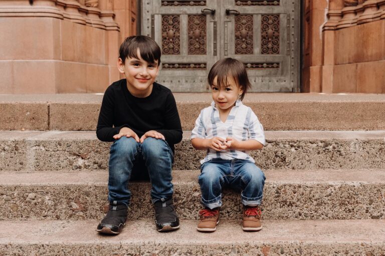 Two children sitting on stone steps smiling.