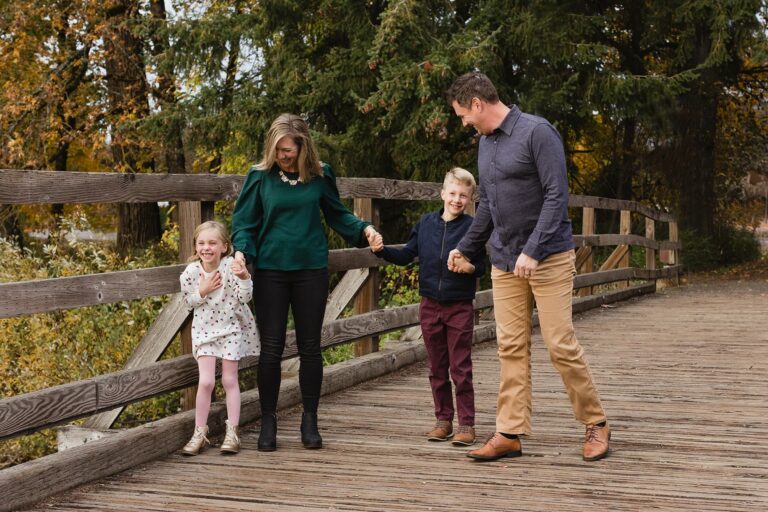 Family walking on wooden bridge in autumn forest