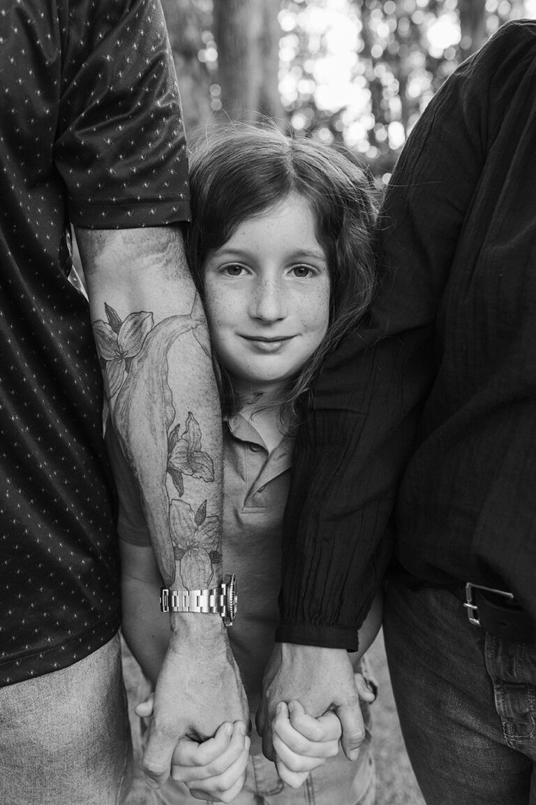 Child holding hands with adults outdoors.