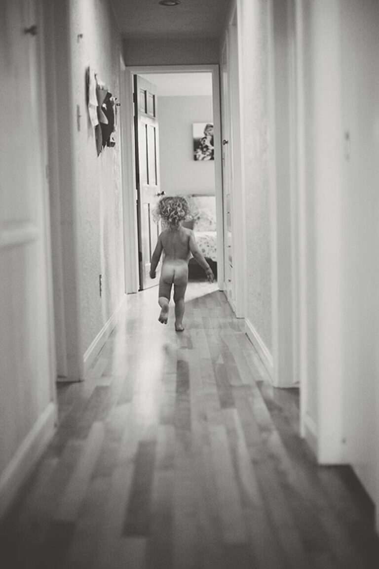 Young girl running through a hallway in black and white.